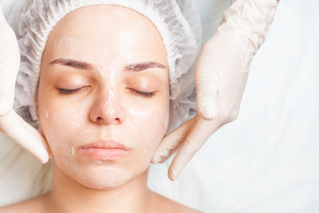 Fototapeta na wymiar Woman in spa salon receiving face treatment with facial cream