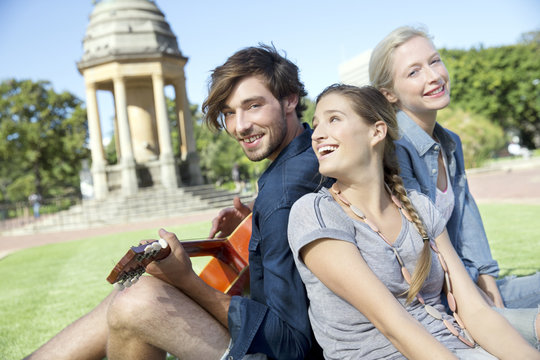 Happy friends with guitar in park