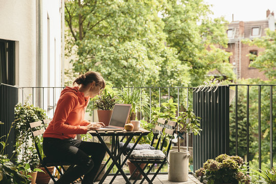 Woman Using Her Laptop On Balcony