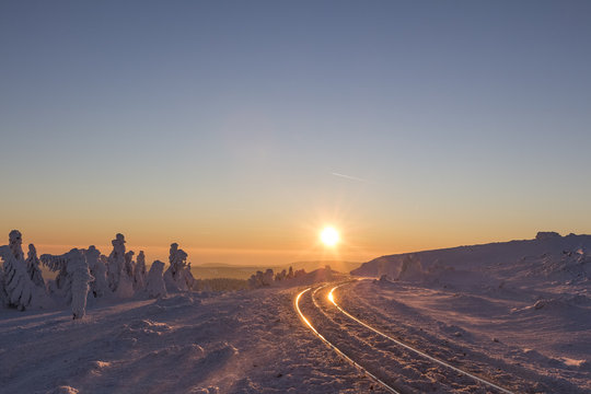 Germany, Saxony-Anhalt, Harz National Park, Brocken, rail tracks of Harz Narrow Gauge Railway in winter against the evening sun