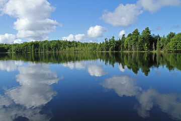 Fototapeta na wymiar Puffy Clouds Reflected in Calm Lake