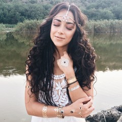 young beautiful woman in a boho style dress posing near lake