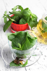 Mint leaves in glass cup on color wooden background