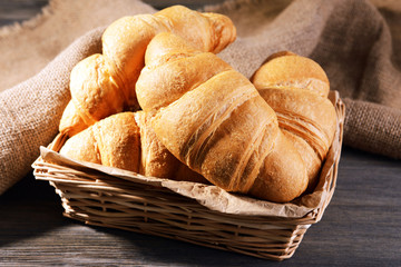 Delicious croissants in wicker basket on table close-up