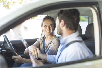 Teenage girl in a car shaking hands with driving inspector