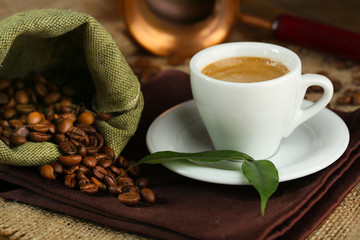 Cup of coffee with beans on table close up
