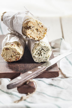 Three rolls of differently flavored compound butters on chopping board