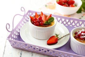 Creme brulee dessert with fresh strawberries and mint leaves, on color wooden background