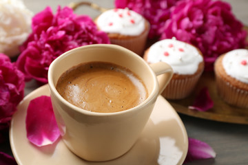 Composition with cup of coffee, muffins and peony flowers on wooden background