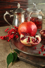 Pomegranate seeds and juice on metal tray and sackcloth, closeup