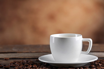 Cup of coffee and beans on blurred background