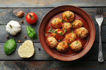 Meat balls with tomato sauce and ingredients on wooden background