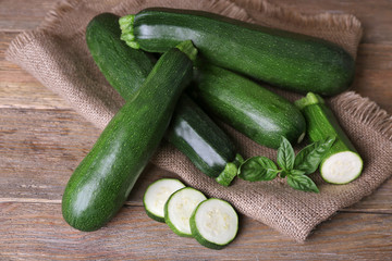 Fresh zucchini with basil on wooden table close up