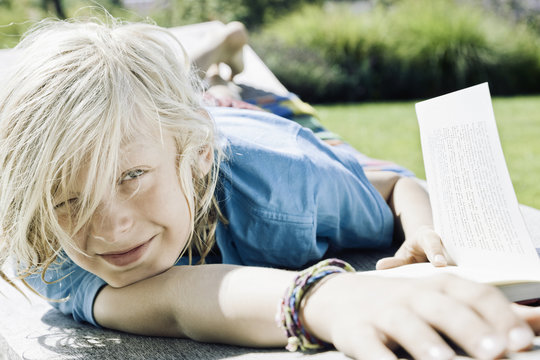 Denmark, Henne Strand, portrait of smiling blond boy with book