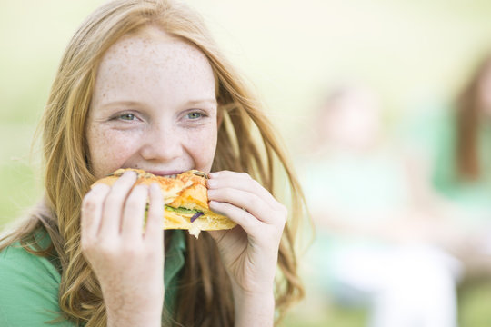 Portrait of girl with red hair eating a sandwich