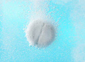 Effervescent painkiller tablet in water, closeup
