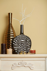 Modern vases with decor on fireplace in room