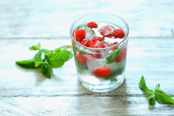 Glass of cold refreshing summer drink with berries and ice cubes on table close up