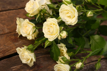 Beautiful small roses on wooden table close up