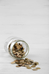 Coins in money jar on wooden background