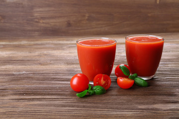 Glasses of tomato juice with vegetables on wooden background