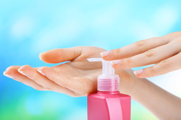 Female hands with cream on colorful blurred background