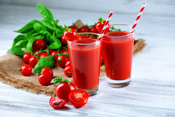 Glasses of tomato juice with vegetables on wooden table close up