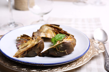 Roasted artichokes on plate, on kitchen table background