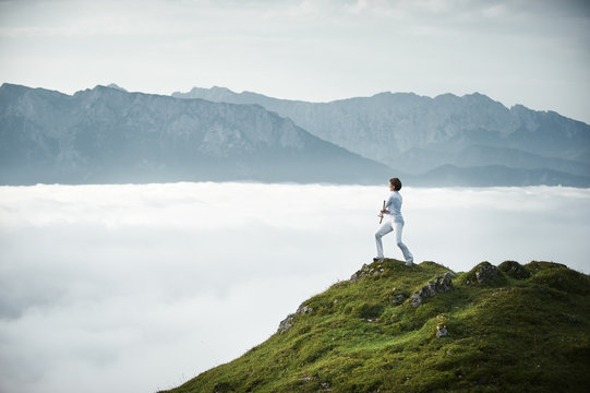 Austria, Kranzhorn, Mid adult woman exercising stick fighting on mountain top