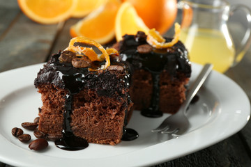 Portion of Cake with Chocolate Glaze and orange on plate, on wooden background