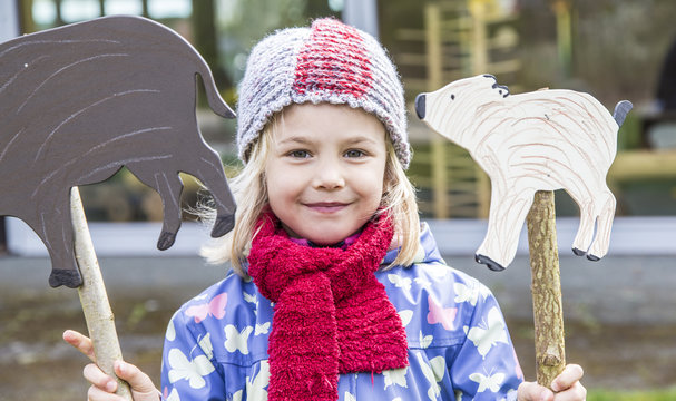 Portrait of smiling little girl holding two signs shaped like boars