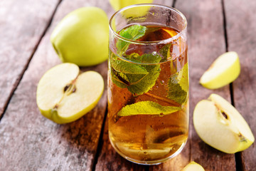 Glass of apple juice with fruits and fresh mint on table close up