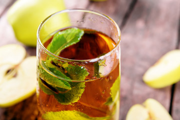 Glass of apple juice with fruits and fresh mint on table close up
