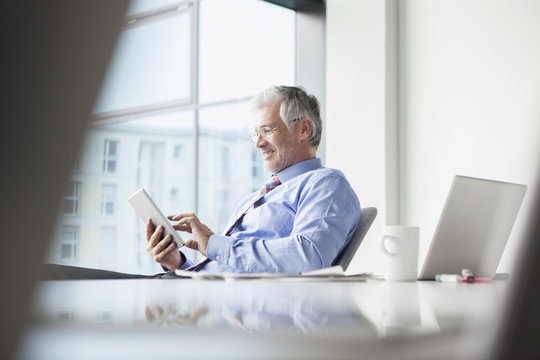 Businessman sitting at , using digital tablet