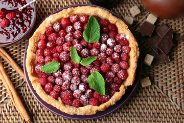 Tart with fresh raspberries, on wooden background