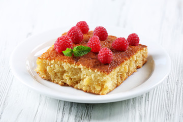 Fresh pie with raspberry in white plate on wooden table, closeup