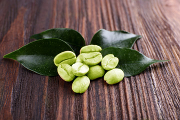 Green coffee beans with leaves on wooden background