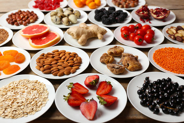 Different products on saucers on wooden table close up
