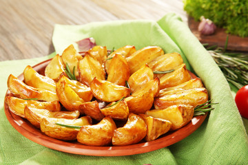 Baked potato wedges on wooden table, closeup