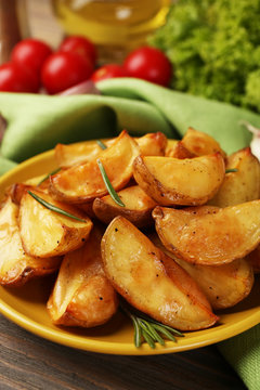 Baked potato wedges on wooden table, closeup