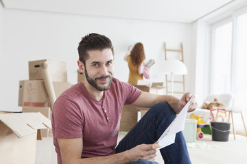 Young couple moving into new flat, man holding ground plan