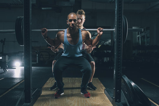Two friends exercising together in gym