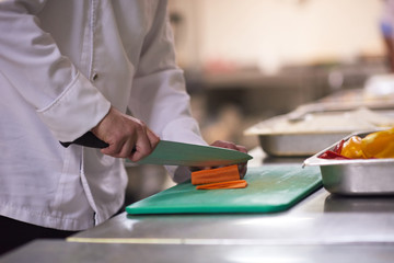 Fototapeta na wymiar chef in hotel kitchen slice vegetables with knife