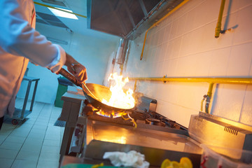 chef in hotel kitchen prepare food with fire