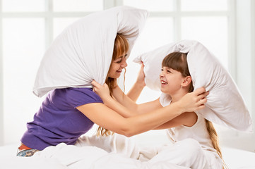  Cheerful mother and daughter having pillow fight