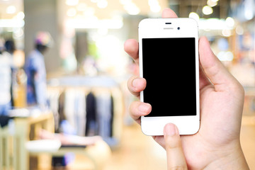 Hand holding smart phone over blur store background, e-commerce