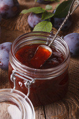 Delicious plum jam in a glass jar on the table close-up. vertical
