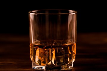 glass of whiskey with ice on a wooden table. Cognac, brandy.