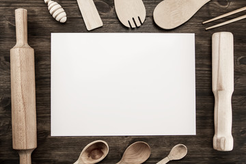 Romantic dinner concept. Top view of blank sheet of paper with silver fork and knife decorated blue curly ribbon on wooden background