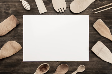 white sheet of paper with utensils on the old wooden background. Mock up